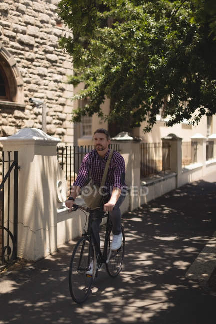 Человек на велосипеде по улице в солнечный день — стоковое фото