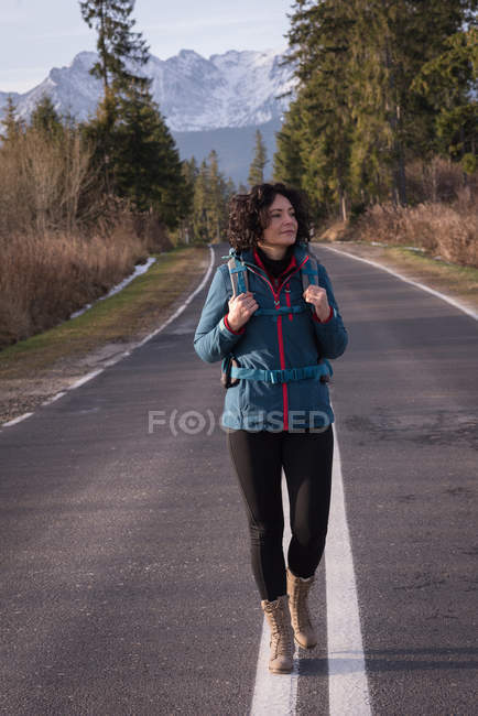 Mulher com mochila andando na estrada no campo — Fotografia de Stock