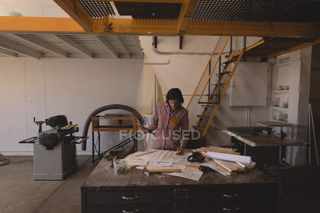 Kunsthandwerkerin arbeitet mit Entwürfen am Schreibtisch in Werkstatt. — Stockfoto