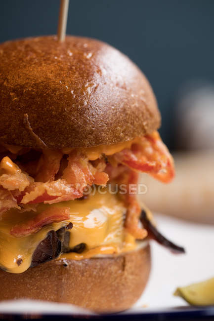 Close-up of burger with bacon served in restaurant. — Stock Photo