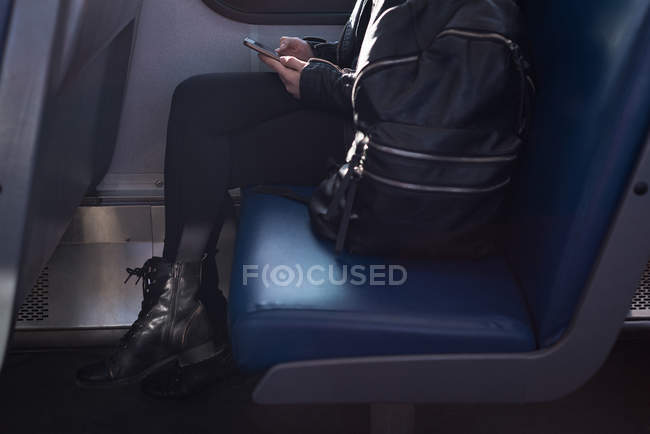 Baixa seção de mulher usando telefone celular enquanto viaja no trem — Fotografia de Stock