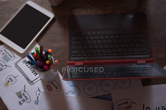 Ordenador portátil, tableta digital y documentos en papel sobre una mesa en la oficina - foto de stock
