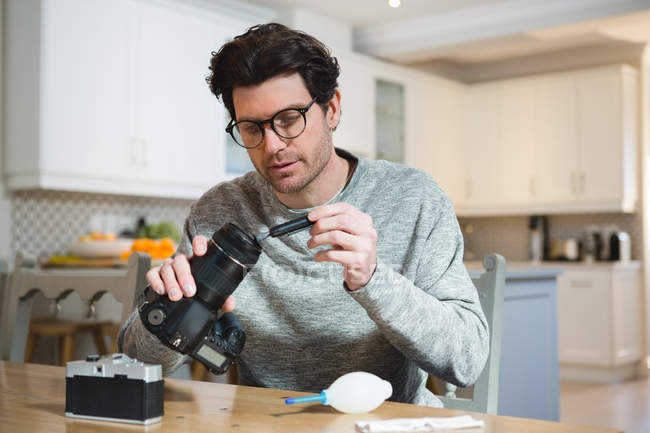 Young an cleaning lens of digital camera at home — Stock Photo
