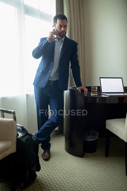 Empresário falando no telefone celular no quarto de hotel — Fotografia de Stock
