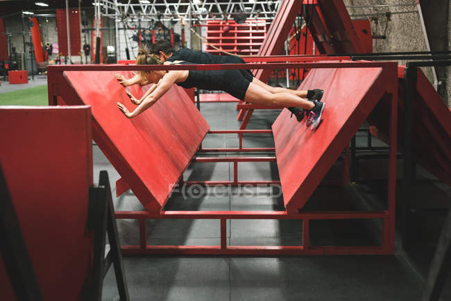 Muskulöses Paar übt Liegestütze an schiefer Wand im Fitnessstudio — Stockfoto