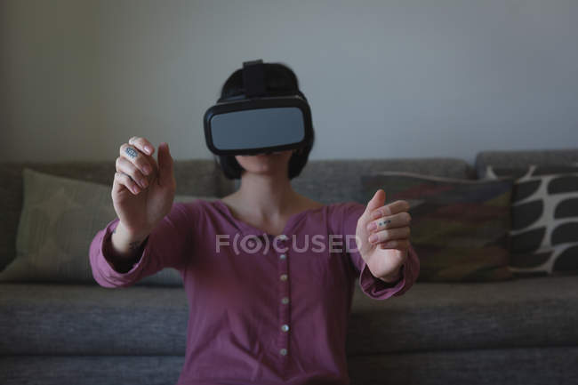 Жінка використовує заголовок віртуальної реальності у вітальні. — стокове фото