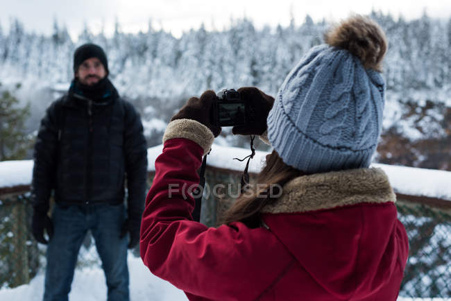 Mulher tirando foto de homem com câmera durante o inverno — Fotografia de Stock