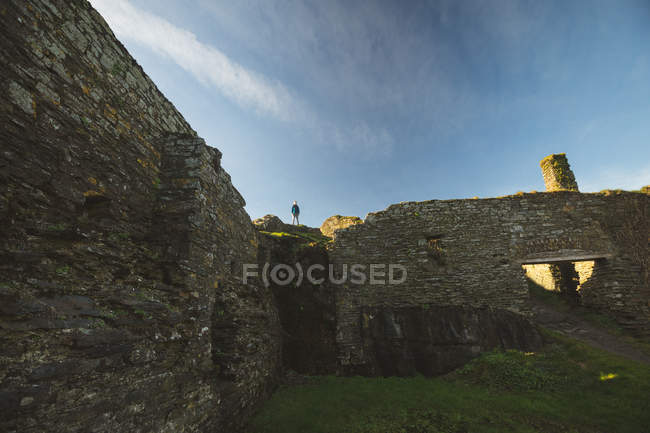 Männliche Wanderer stehen auf alten Ruinen im Sonnenlicht — Stockfoto