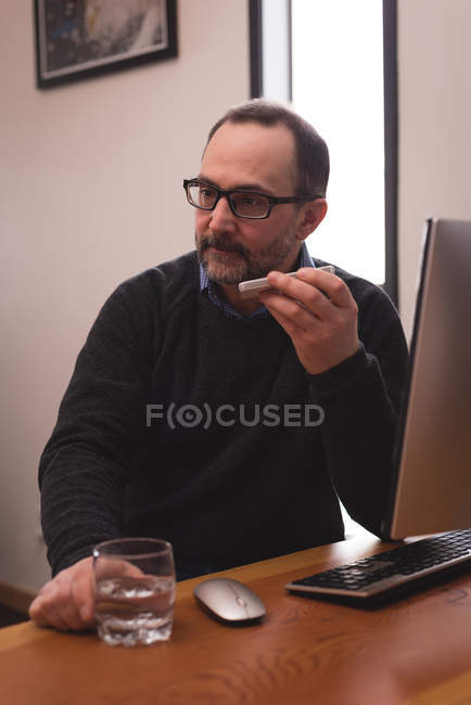 Male executive talking on mobile phone at desk in office — Stock Photo
