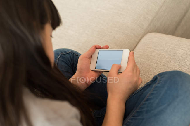 Ragazza che utilizza il telefono cellulare in soggiorno a casa — Foto stock