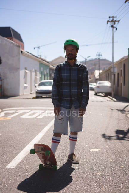 Man standing with skateboard in street in sunlight — Stock Photo