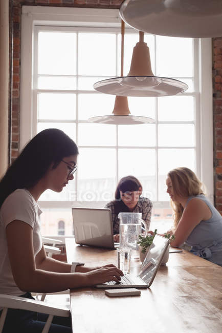 Executivo feminino usando laptop no escritório criativo — Fotografia de Stock