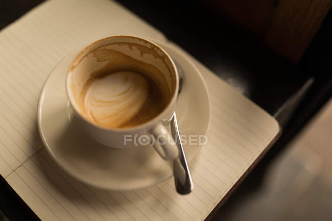Empty cup of coffee with saucer and spoon in cafe on diary — Stock Photo