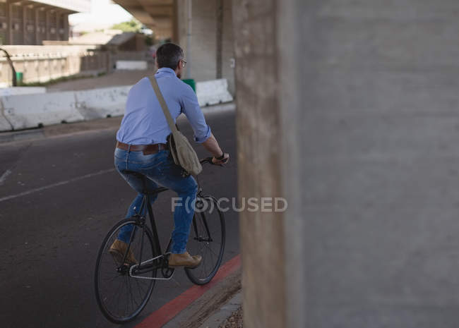 Вид ззаду людини, що їде на велосипеді на вулиці — стокове фото