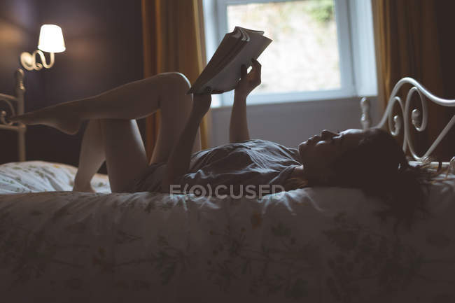 Mulher lendo um livro no quarto em casa — Fotografia de Stock