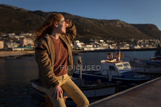 Mujer protegiendo los ojos mientras mira el muelle a la luz del sol - foto de stock