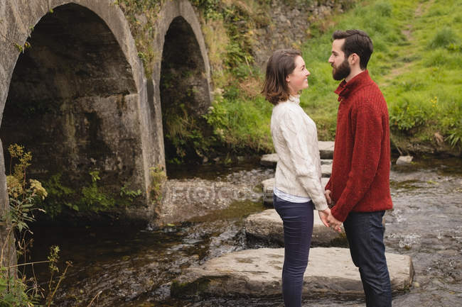 Affectionate couple standing on rock in the river — Stock Photo