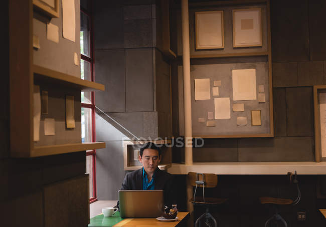Hombre de negocios asiático usando portátil en la cafetería - foto de stock