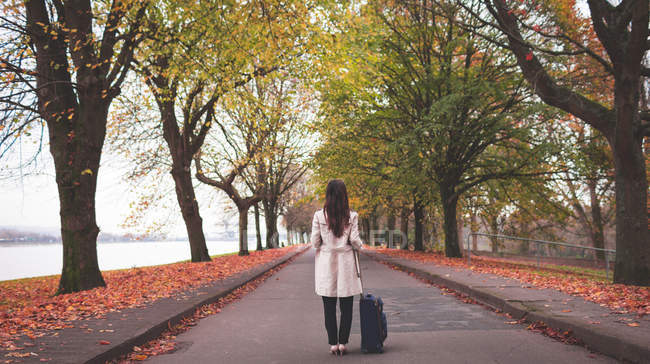 Businesswoman with baggage standing on street during autumn — Stock Photo