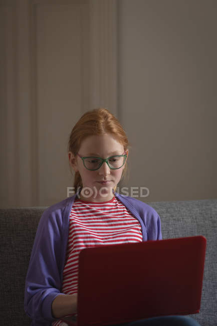 Девочка, использующая ноутбук в гостиной дома — стоковое фото