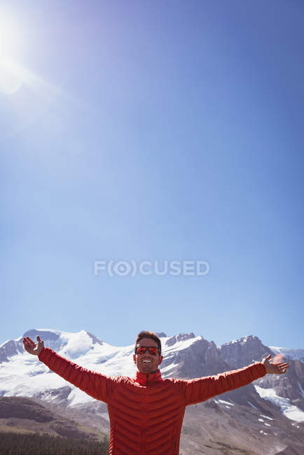 Man in sunglasses standing with arms outstretched on a sunny day — Stock Photo