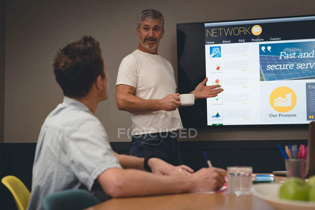 Empresário dando apresentação a colegas em sala de reunião no escritório — Fotografia de Stock