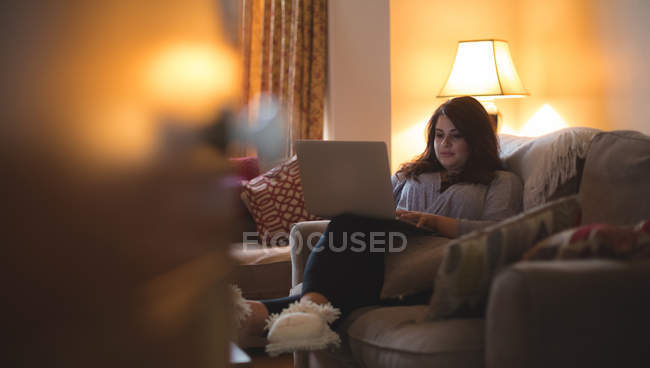 Жіночий відеоблогер сидить на дивані, використовуючи ноутбук вдома — стокове фото