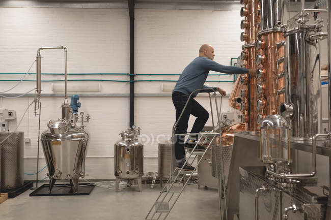 Travailleur masculin vérifiant la machine de distillerie dans l'usine — Photo de stock