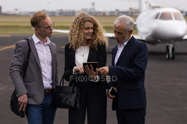 Business people discussing over digital tablet on runaway — Stock Photo