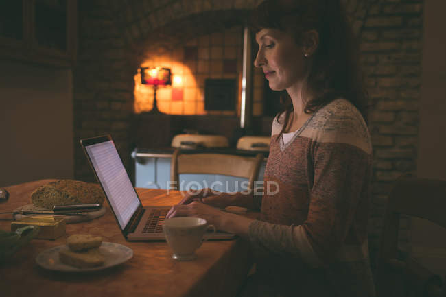 Frau benutzt Laptop beim Frühstück zu Hause — Stockfoto
