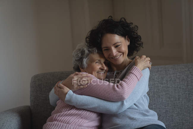 Madre e figlia si abbracciano in salotto a casa — Foto stock
