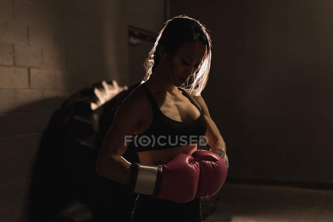 Entschlossene Frau steht mit Boxhandschuhen im Fitnessstudio — Stockfoto