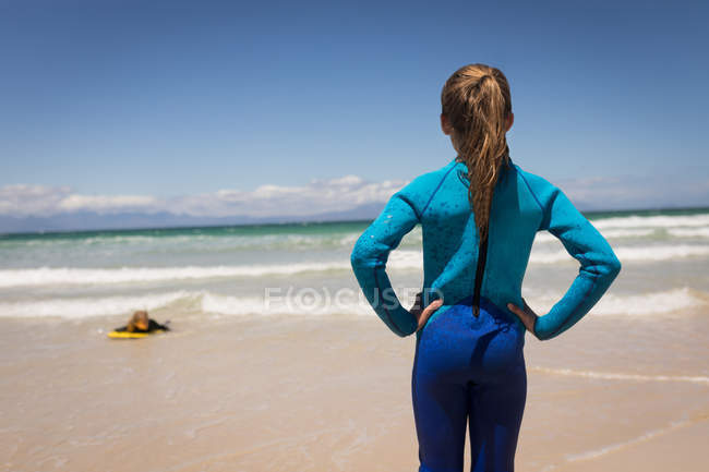 Rear view of girl looking at her sister while surfing in sea — Stock Photo