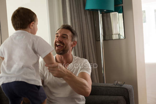 Father and son playing together in living room at home — Stock Photo