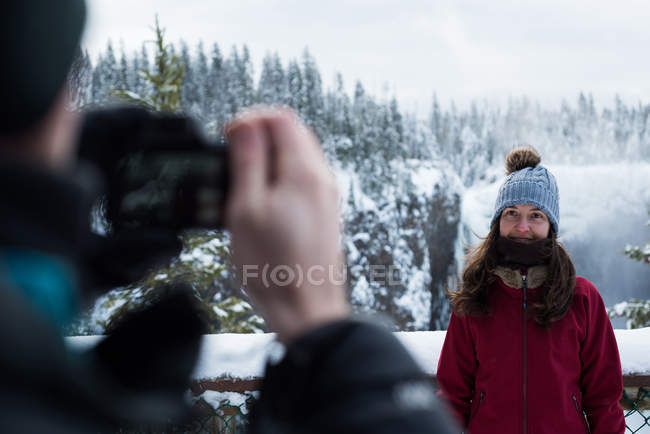 Hombre tomando fotos de mujer con cámara durante el invierno - foto de stock