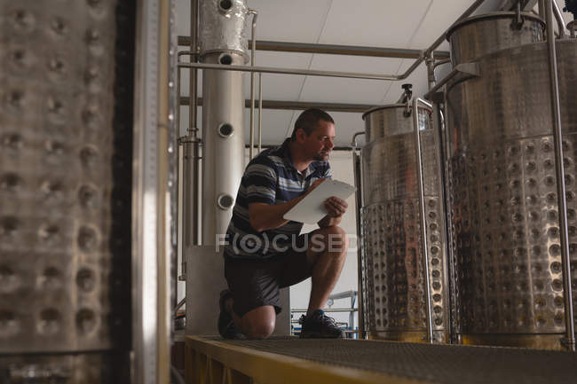 Trabalhador masculino observando a pressão da destilaria na área de transferência na fábrica — Fotografia de Stock