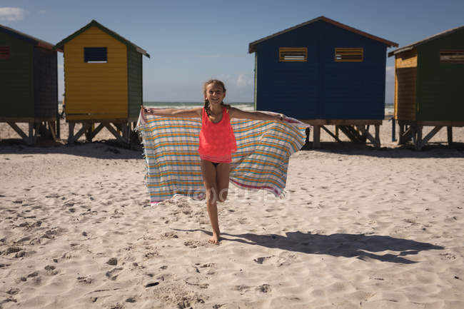 Porträt eines glücklichen Mädchens, das mit Handtuch am Strand steht — Stockfoto