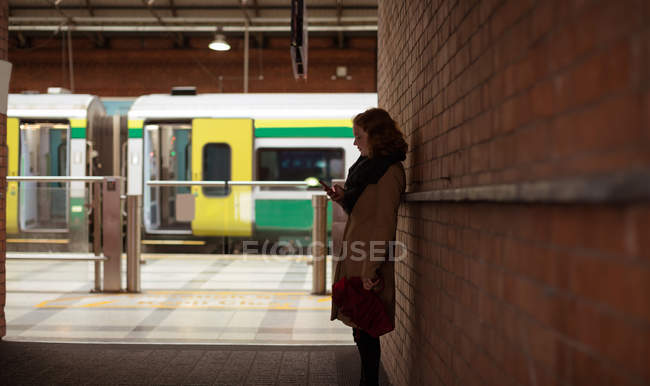 Junge Frau benutzt Handy am Bahnhof — Stockfoto