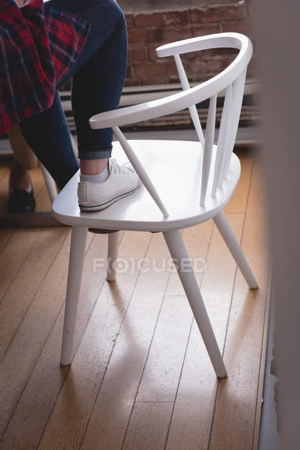 Жінка-виконавчий стоячи на стільці в творчому офісі — стокове фото