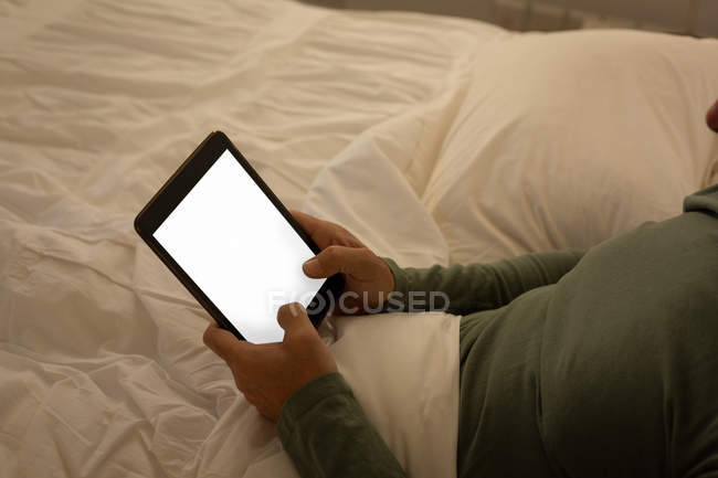 Homem sênior usando tablet digital no quarto em casa — Fotografia de Stock