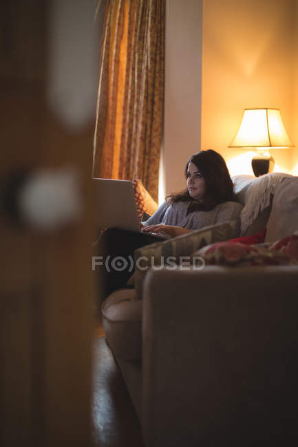 Vloggerin sitzt auf Sofa und benutzt Laptop zu Hause — Stockfoto