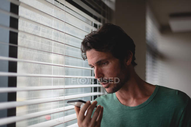 Young man talking on mobile phone at home — Stock Photo
