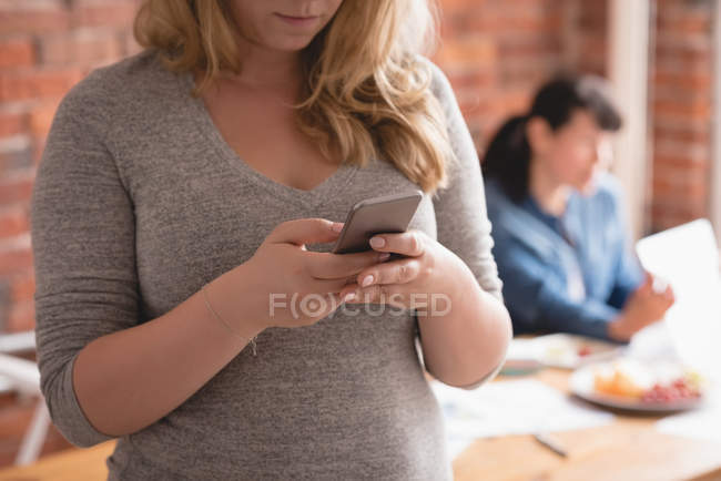 Executivo feminino usando telefone celular no escritório criativo — Fotografia de Stock