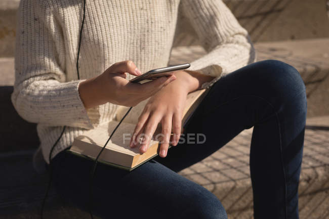 Mid section of teenage girl using mobile phone on staircase — Stock Photo