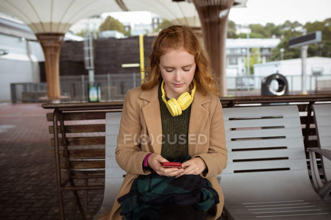 Jovem mulher usando seu telefone celular na estação ferroviária — Fotografia de Stock