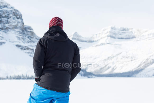 Vista posteriore dell'alpinista maschio in piedi su una montagna innevata durante l'inverno — Foto stock
