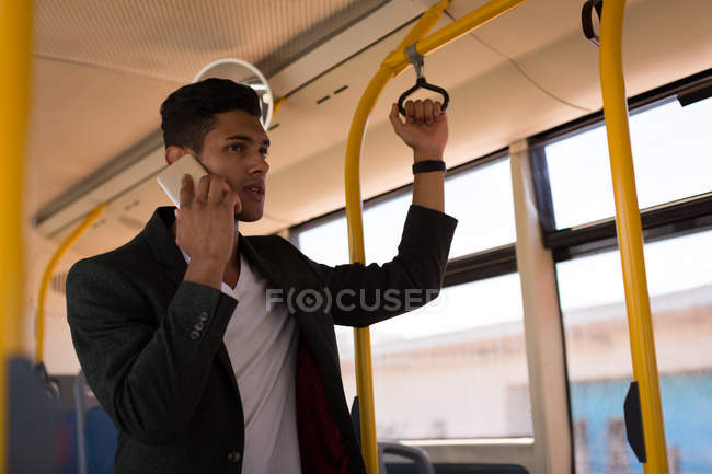 Jeune homme d'affaires parlant sur un téléphone portable pendant un voyage en bus — Photo de stock