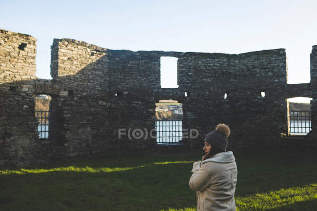 Young woman standing near old ruins in sunlight. — Stock Photo