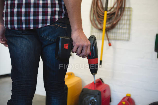 Seção média de carpinteiro masculino segurando máquina de broca na oficina — Fotografia de Stock