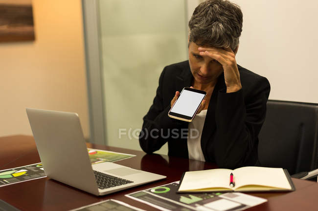 Donna d'affari matura che parla al cellulare in ufficio — Foto stock